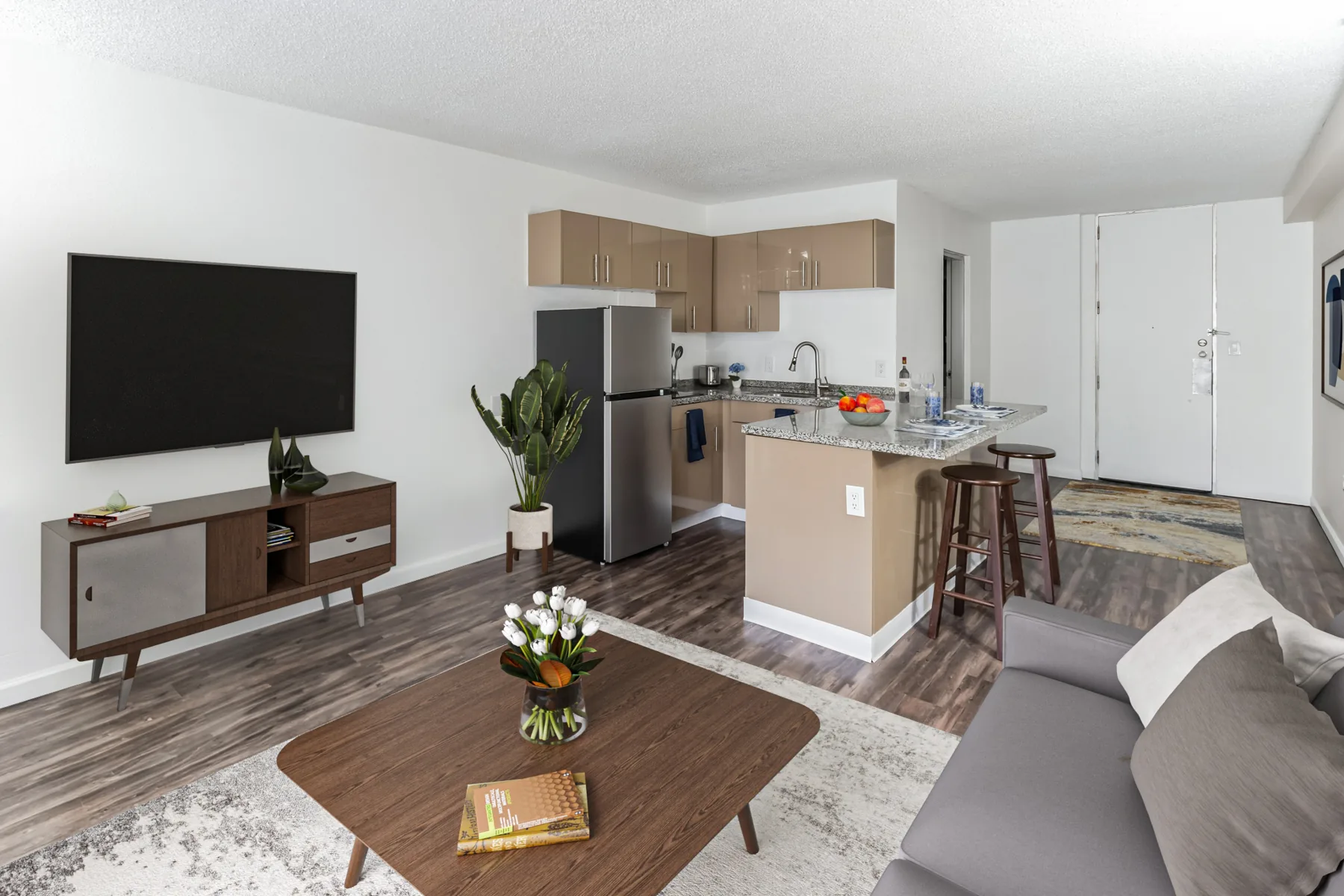 Living room with TV wall and open kitchen with breakfast bar at ABQ Encore Apartments