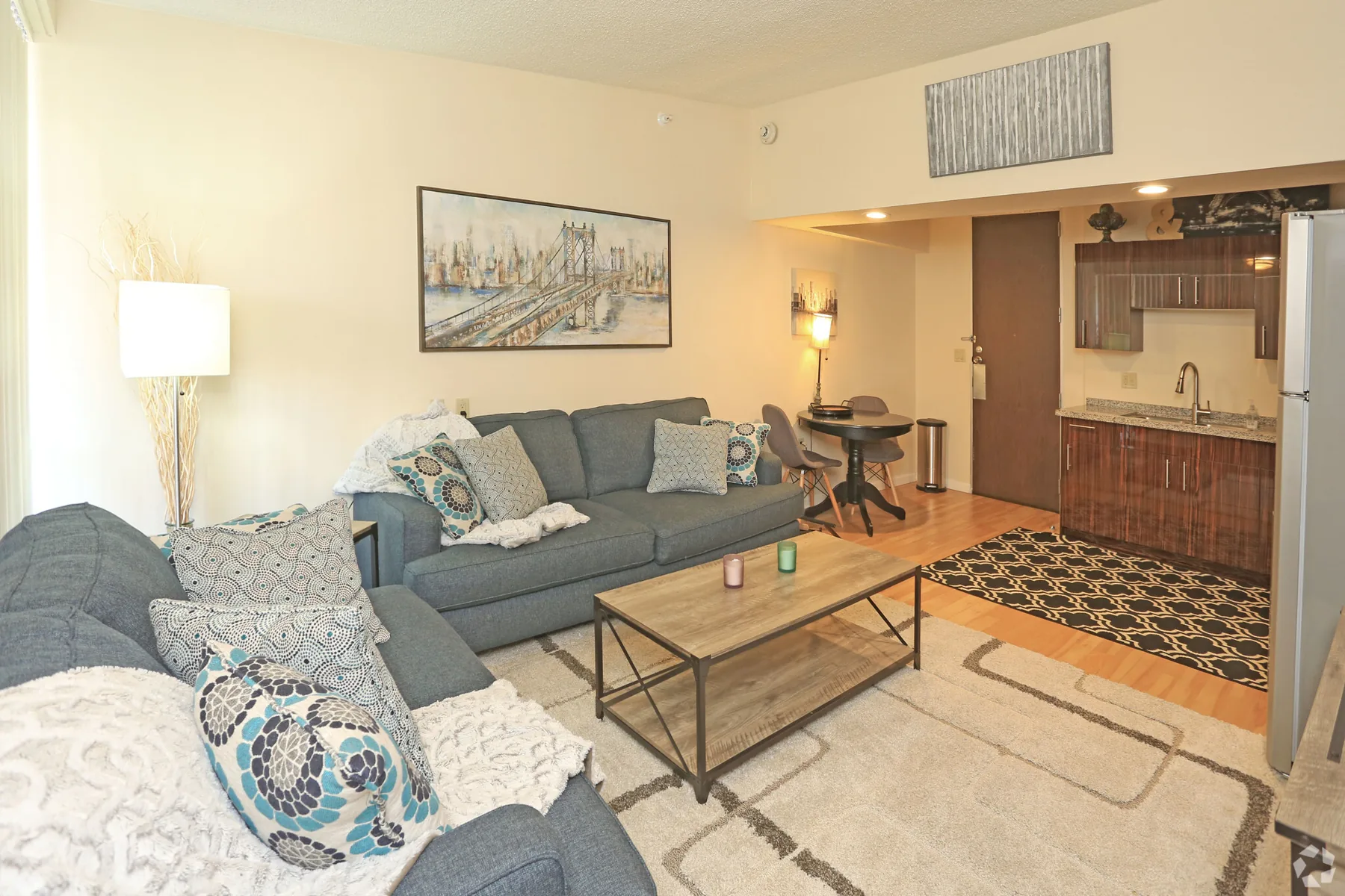 Furnished studio living area with sectional sofa, dining table and kitchenette at ABQ Encore Apartments